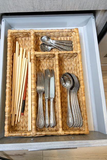 wicker water hyacinth cutlery tray with silverware and chopsticks inside a drawer.